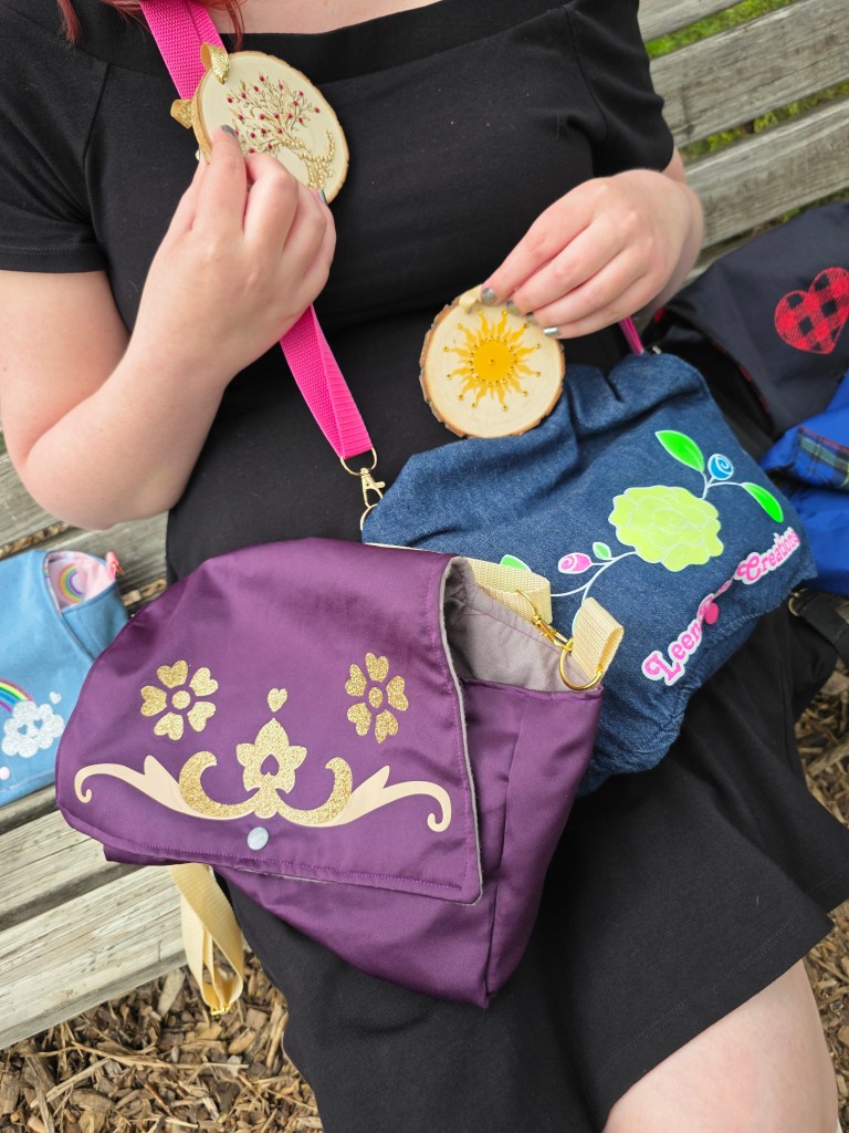 LeenaRose surrounded and covered by five handmade diaper purses and holding up two Winter Solstice ornaments